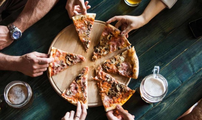 a group of people eating pizza